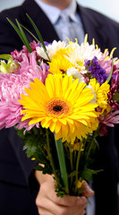 dressed up man presenting flowers