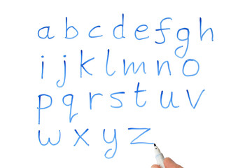 a teacher writing the alphabet on a whiteboard.