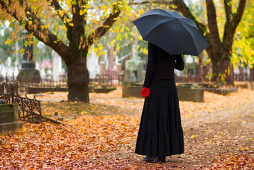 woman in mourning at cemetery in fall - obrazy, fototapety, plakaty