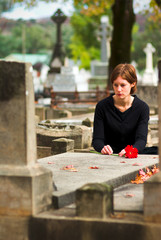 woman laying flower on grave