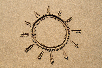 a sun symbol drawn on a sandy beach.