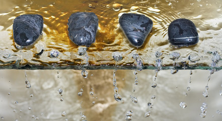 zen stone pebbles on edge of waterfall drops water