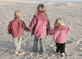 three kids walking the beach together, muted tones