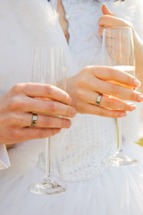 two hands with wedding rings holding champagne gla