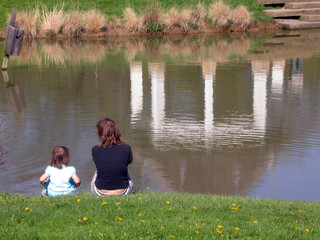 mother and daughter sitting by a pond