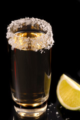 glass of tequila with salt around rim and a lime