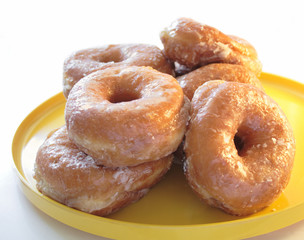 fresh glazed doughnuts on a yellow plate