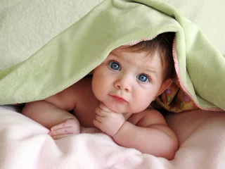 Fototapeten beautiful baby looking out from under blanket © Jamey Ekins