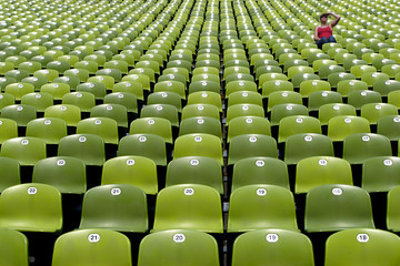 Naklejka premium zielone siedzenia stadionu z kobietą widza