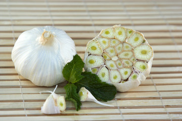 Fototapeta na wymiar raw garlic on a bamboo surface with mint leaves