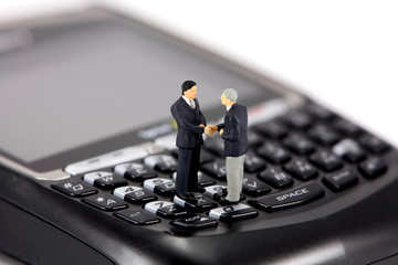 two miniature businessmen shaking hands