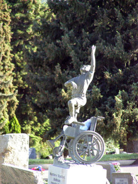 statue of a boy standing on a wheelchair at grave