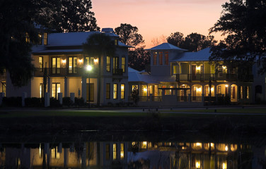 luxury homes reflecting on pond at sunset