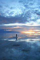 person watching sunset over wet salt flats