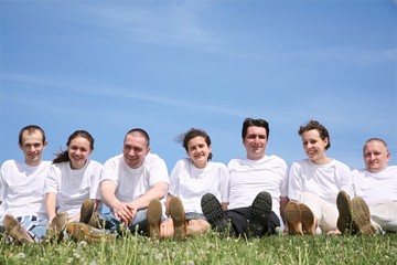 Group of friends in white T-shorts have a rest on a grass