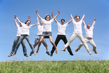 Fototapeta na wymiar Seven friends in white T-shorts swing hands in a jump