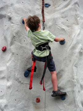 Young boy scaling a climbing wall post haste