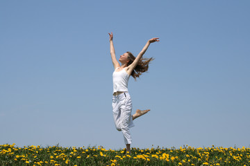 Natural beauty. Young woman dancing in a flowering field.