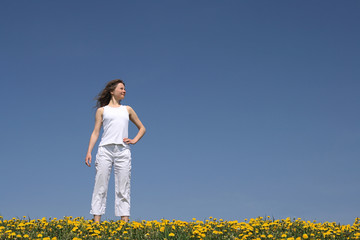 Fototapeta premium Calm young woman standing in a flowering spring field.