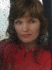 Girl looks thru waterdropped widow glass in rainy weather
