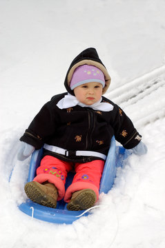 A toddler girl on her first ride in a snow.