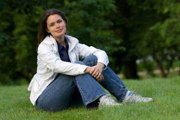 Obraz premium Pretty brunette relaxing on a fresh grass in a park
