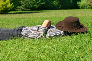 A child lays in grassy field taking a rest or siesta.