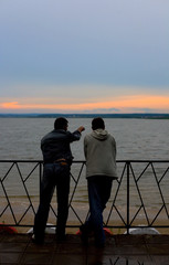 Fototapeta premium Two men on a river bay look at sunset #1