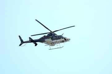 A Private Heliocopter flying against a Blue Sky