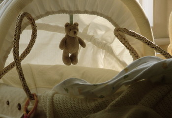 Baby cradle or moses basket with hanging teddy bear