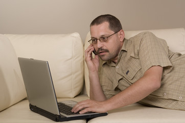 man working on a laptop and calling by phone