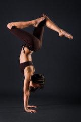Young female gymnast is stretching her body in a studio