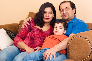 An East-Indian couple site in their living room with their son