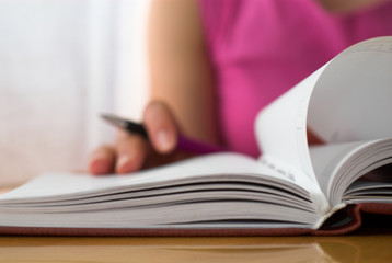 Young female is writing notes and planning her schedule.