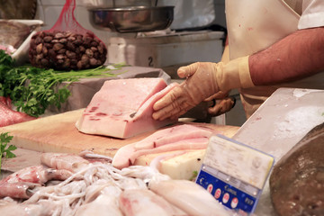 cutting tuna fillet in a fishmonger´s with a lot of fish