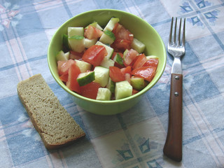 Cucumber and tomatoes salad with bread and spoon