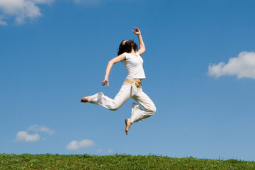 Fototapeta na wymiar happy young woman is jumping in green grass