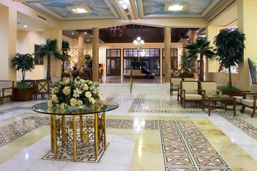 Hall in hotel with marble floor and flowers on the table
