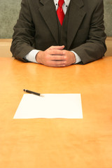 Business-man sitting at the desk, open contract infront of him.