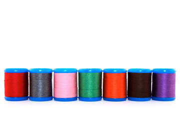 Row of colorful thread spools, on white background