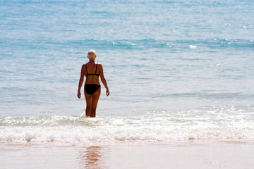 blonde kurzhaarige frau geht ins meer
