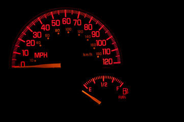 A red speedometer and gas gauge on an automobile dashboard.