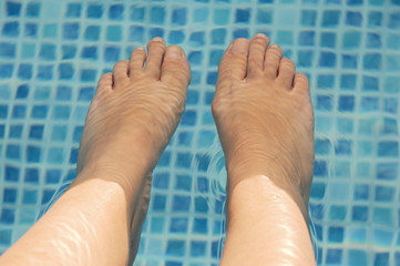 feet refreshing in swimming pool in summer