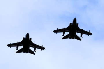 A silhouette of two Royal Air force RAF Panavia Tornado jet fighters against a blue sky. - obrazy, fototapety, plakaty