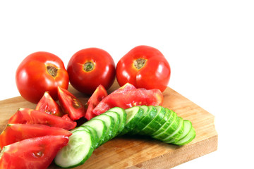 tomatos and cucumbers on a wooden plate isolated on white