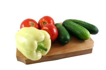 tomatos cucumbers and a yellow pepper on a wooden plate