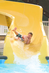 A young boy sliding down a water slide.
