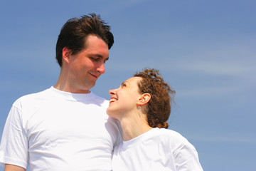 Obraz premium Happy couple clothed in white t-shirts against a blue sky
