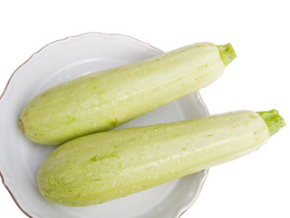 Two green young vegetable marrows on a plate 