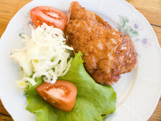 Fried meat with vegetables in utensils on a wooden table